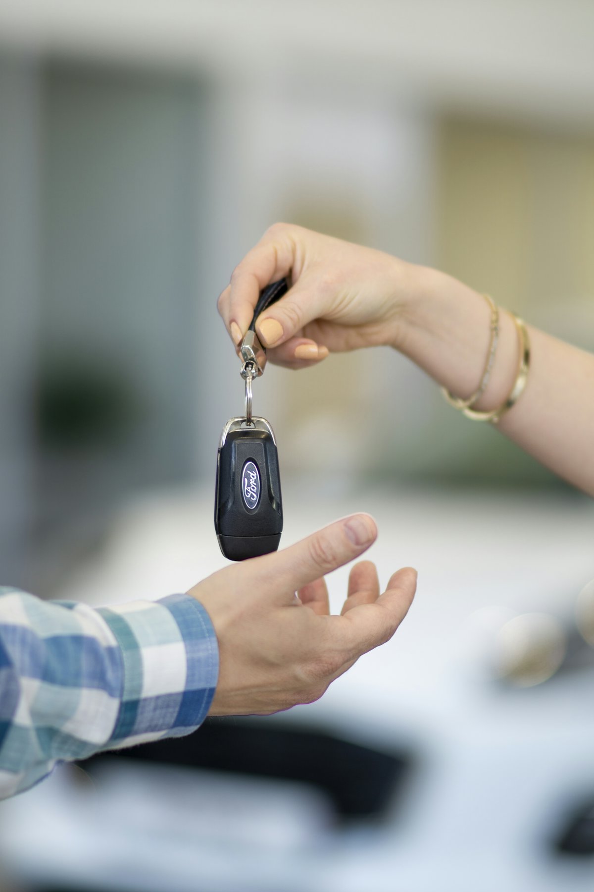 One person handing over a set of keys to another — a rental pickup moment